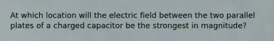 At which location will the electric field between the two parallel plates of a charged capacitor be the strongest in magnitude?