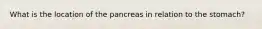 What is the location of the pancreas in relation to the stomach?