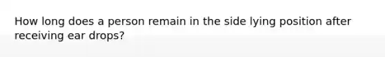 How long does a person remain in the side lying position after receiving ear drops?