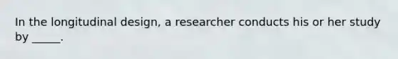 In the longitudinal design, a researcher conducts his or her study by _____.