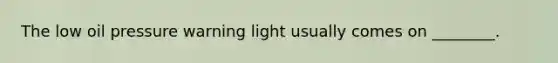 The low oil pressure warning light usually comes on ________.