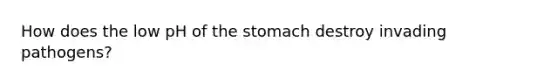 How does the low pH of the stomach destroy invading pathogens?