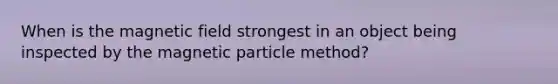 When is the magnetic field strongest in an object being inspected by the magnetic particle method?