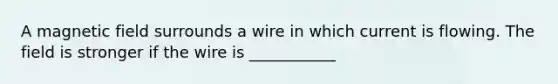 A magnetic field surrounds a wire in which current is flowing. The field is stronger if the wire is ___________