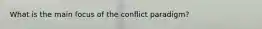 What is the main focus of the conflict paradigm?