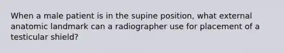 When a male patient is in the supine position, what external anatomic landmark can a radiographer use for placement of a testicular shield?