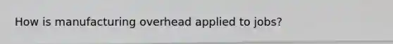 How is manufacturing overhead applied to jobs?