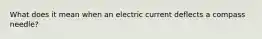 What does it mean when an electric current deflects a compass needle?