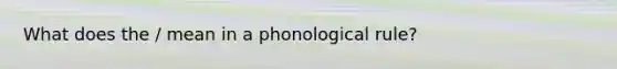 What does the / mean in a phonological rule?