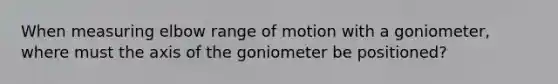 When measuring elbow range of motion with a goniometer, where must the axis of the goniometer be positioned?