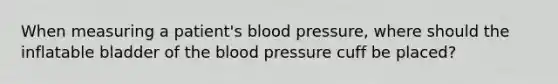 When measuring a patient's blood pressure, where should the inflatable bladder of the blood pressure cuff be placed?