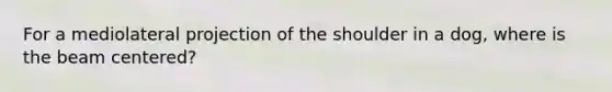 For a mediolateral projection of the shoulder in a dog, where is the beam centered?