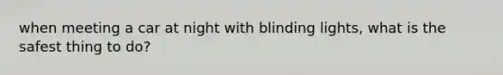 when meeting a car at night with blinding lights, what is the safest thing to do?