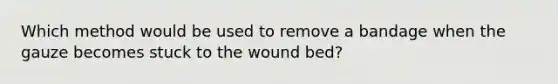 Which method would be used to remove a bandage when the gauze becomes stuck to the wound bed?