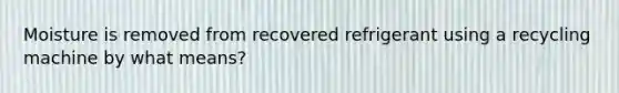 Moisture is removed from recovered refrigerant using a recycling machine by what means?