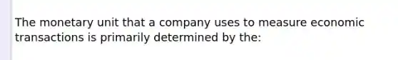 The monetary unit that a company uses to measure economic transactions is primarily determined by the: