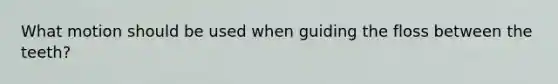 What motion should be used when guiding the floss between the teeth?
