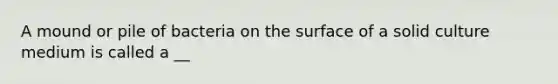 A mound or pile of bacteria on the surface of a solid culture medium is called a __