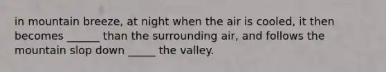 in mountain breeze, at night when the air is cooled, it then becomes ______ than the surrounding air, and follows the mountain slop down _____ the valley.