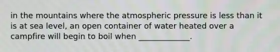 in the mountains where the atmospheric pressure is less than it is at sea level, an open container of water heated over a campfire will begin to boil when _____________.