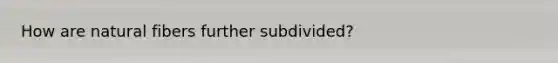 How are natural fibers further subdivided?