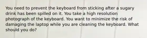 You need to prevent the keyboard from sticking after a sugary drink has been spilled on it. You take a high resolution photograph of the keyboard. You want to minimize the risk of damaging the laptop while you are cleaning the keyboard. What should you do?