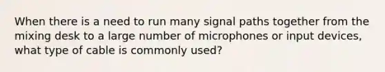 When there is a need to run many signal paths together from the mixing desk to a large number of microphones or input devices, what type of cable is commonly used?