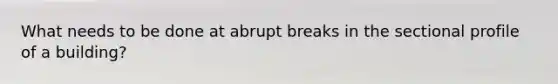 What needs to be done at abrupt breaks in the sectional profile of a building?