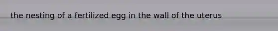 the nesting of a fertilized egg in the wall of the uterus