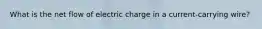 What is the net flow of electric charge in a current-carrying wire?