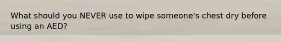 What should you NEVER use to wipe someone's chest dry before using an AED?
