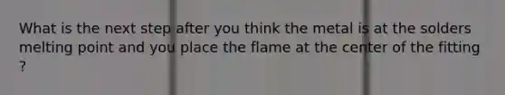 What is the next step after you think the metal is at the solders melting point and you place the flame at the center of the fitting ?