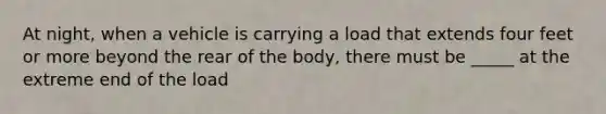 At night, when a vehicle is carrying a load that extends four feet or more beyond the rear of the body, there must be _____ at the extreme end of the load