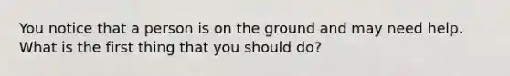 You notice that a person is on the ground and may need help. What is the first thing that you should do?