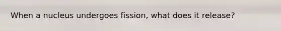When a nucleus undergoes fission, what does it release?