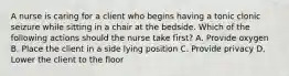 A nurse is caring for a client who begins having a tonic clonic seizure while sitting in a chair at the bedside. Which of the following actions should the nurse take first? A. Provide oxygen B. Place the client in a side lying position C. Provide privacy D. Lower the client to the floor