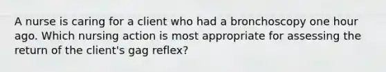 A nurse is caring for a client who had a bronchoscopy one hour ago. Which nursing action is most appropriate for assessing the return of the client's gag reflex?