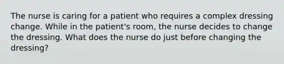 The nurse is caring for a patient who requires a complex dressing change. While in the patient's room, the nurse decides to change the dressing. What does the nurse do just before changing the dressing?