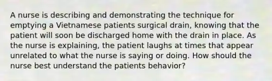 A nurse is describing and demonstrating the technique for emptying a Vietnamese patients surgical drain, knowing that the patient will soon be discharged home with the drain in place. As the nurse is explaining, the patient laughs at times that appear unrelated to what the nurse is saying or doing. How should the nurse best understand the patients behavior?