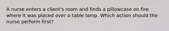 A nurse enters a client's room and finds a pillowcase on fire where it was placed over a table lamp. Which action should the nurse perform first?