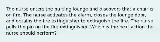 The nurse enters the nursing lounge and discovers that a chair is on fire. The nurse activates the alarm, closes the lounge door, and obtains the fire extinguisher to extinguish the fire. The nurse pulls the pin on the fire extinguisher. Which is the next action the nurse should perform?