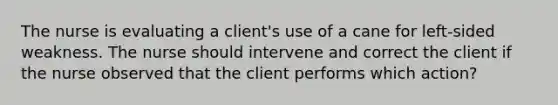 The nurse is evaluating a client's use of a cane for left-sided weakness. The nurse should intervene and correct the client if the nurse observed that the client performs which action?