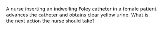 A nurse inserting an indwelling Foley catheter in a female patient advances the catheter and obtains clear yellow urine. What is the next action the nurse should take?