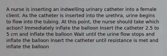 A nurse is inserting an indwelling urinary catheter into a female client. As the catheter is inserted into the urethra, urine begins to flow into the tubing. At this point, the nurse should take which action? Immediately inflate the balloon Insert the catheter 2.5 to 5 cm and inflate the balloon Wait until the urine flow stops and inflate the balloon Insert the catheter until resistance is met and inflate the balloon