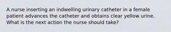 A nurse inserting an indwelling urinary catheter in a female patient advances the catheter and obtains clear yellow urine. What is the next action the nurse should take?