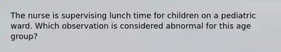 The nurse is supervising lunch time for children on a pediatric ward. Which observation is considered abnormal for this age group?