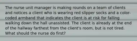 The nurse unit manager is making rounds on a team of clients and notices a client who is wearing red slipper socks and a color-coded armband that indicates the client is at risk for falling walking down the hall unassisted. The client is already at the end of the hallway farthest from the client's room, but is not tired. What should the nurse do first?