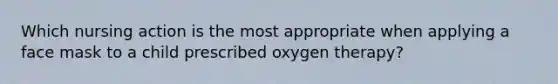 Which nursing action is the most appropriate when applying a face mask to a child prescribed oxygen therapy?