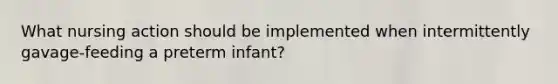 What nursing action should be implemented when intermittently gavage-feeding a preterm infant?