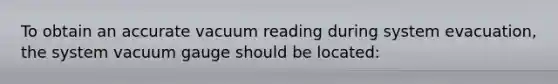 To obtain an accurate vacuum reading during system evacuation, the system vacuum gauge should be located: